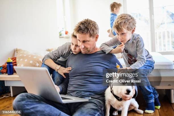 father using laptop at home with children watching - lebens ausgewogenheit stock-fotos und bilder