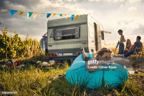 girl lying on inflatable lounger next to caravan in the countryside - caravan stockfoto's en -beelden