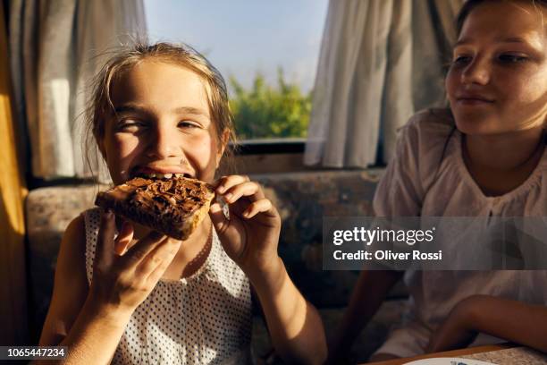 girl in caravan watching her sister eating a toast with chocolate spread - caravan holiday family imagens e fotografias de stock