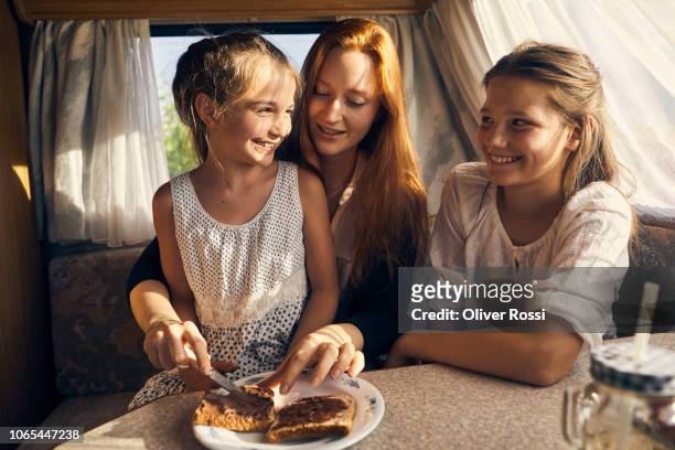 young woman in caravan preparing a toast with chocolate spread for her sister - chocolate spread stock pictures, royalty-free photos & images