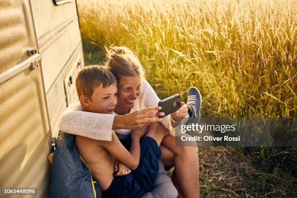 happy mother and son sitting with cell phone at a caravan - family caravan stockfoto's en -beelden