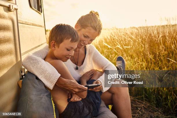 happy mother and son sitting with cell phone at a caravan - caravan holiday family imagens e fotografias de stock