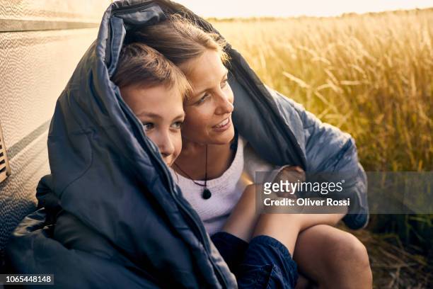 mother and son sharing a sleeping bag at a caravan - protezione foto e immagini stock