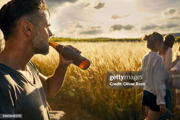 man with his family drinking a bottle of beer in remote landscape - bottle beer foto e immagini stock