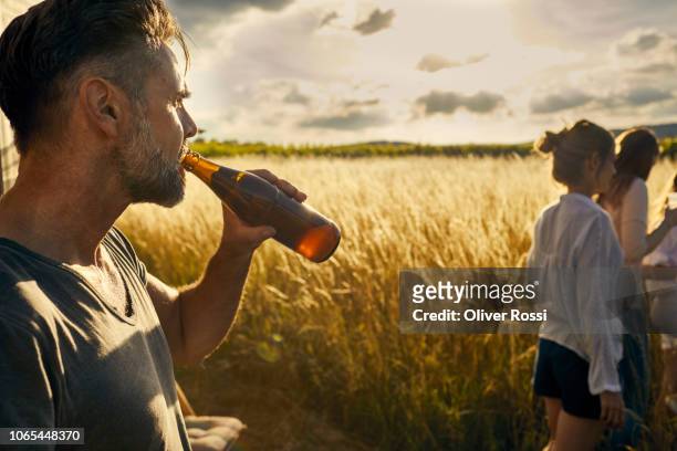 man with his family drinking a bottle of beer in remote landscape - drinking from bottle stock pictures, royalty-free photos & images