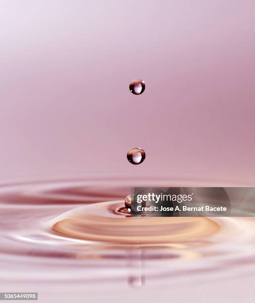 group of drops on line suspended in the air, falling down on a water surface that forms figures and abstract forms, on a pale pink background. - onde sinusoïdale photos et images de collection
