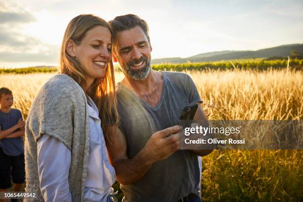 man showing cell phone to woman in rural landscape - rural couple young stockfoto's en -beelden