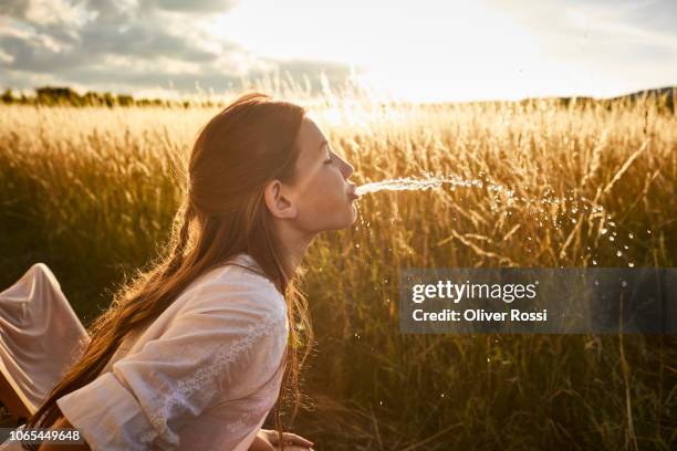 girl spitting water in rural landscape - saliva stock pictures, royalty-free photos & images