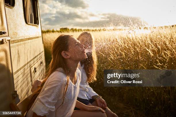 girl with mother at caravan spitting water - family caravan stockfoto's en -beelden