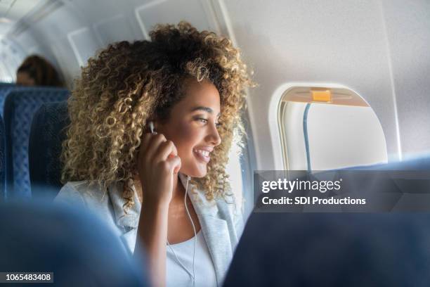 a young woman look out a plane window smiles - passageiro imagens e fotografias de stock