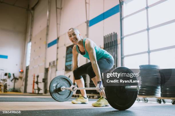 mature woman practicing deadlifts in cross training gym - barbell stock pictures, royalty-free photos & images