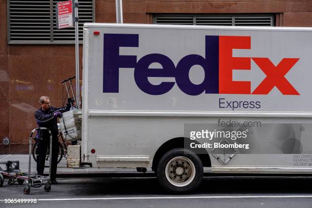 Driver for an independent contractor to FedEx Corp. Unloads United States Postal Service bins from a delivery truck in New York, U.S., on Monday,...