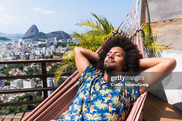 hombre brasileño duerme en hamaca, pão de açúcar en distancia - hamaca fotografías e imágenes de stock