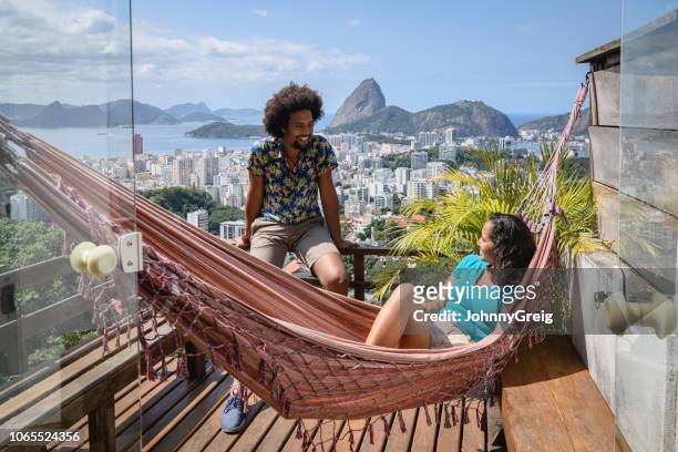jeune couple sur balcon avec vue sur rio en arrière-plan - rio de janeiro photos et images de collection