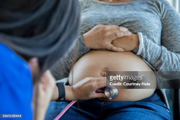 schwanger afroamerikaner mitte erwachsenen patienten untersucht mit einem stethoskop - midwifery stock-fotos und bilder