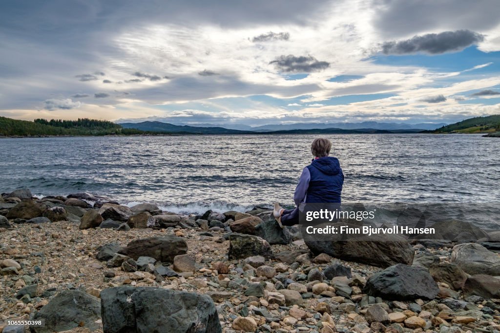Woman sitting at the seashore looking into to the sunset