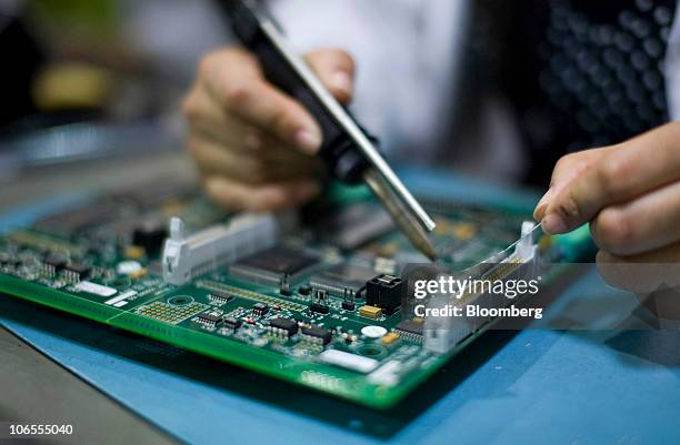 An employee solders a component on to a printed circuit board at Texcel Technology Plc.'s factory in Dartford, U.K., on Thursday, Nov. 4, 2010. The...