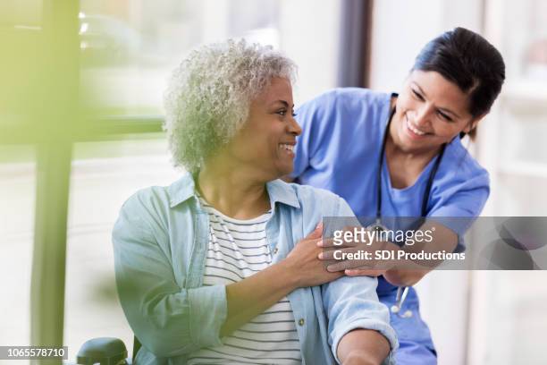 senior woman in wheelchair receives medical help for injury - happiness therapy stock pictures, royalty-free photos & images