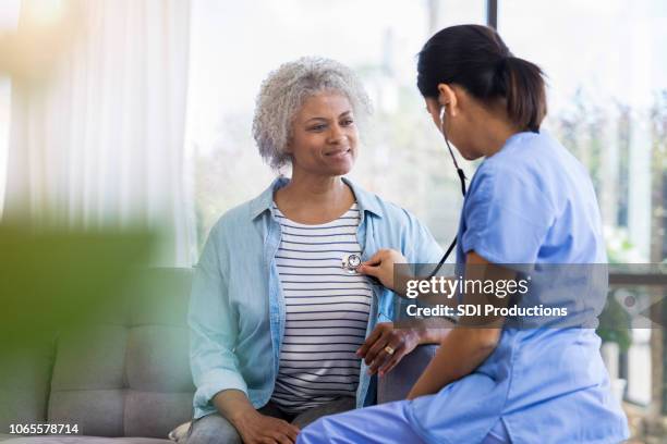 mulher sênior aguarda pacientemente enquanto médico ouve batimento cardíaco - ouvindo batidas do coração - fotografias e filmes do acervo