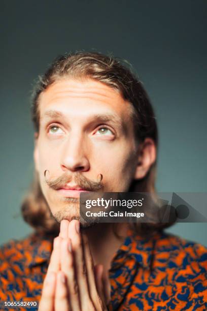 portrait hopeful young man with handlebar mustache praying - handlebar moustache stock pictures, royalty-free photos & images