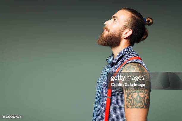 curious hipster man with beard and shoulder tattoo looking up - tattoo shoulder stock pictures, royalty-free photos & images