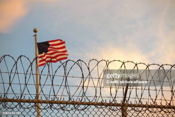 October 2018, Cuba, Guantanamo Bay: A US-American flag blows behind a barbed wire fence in the wind. The infamous camp has now existed for almost 17...