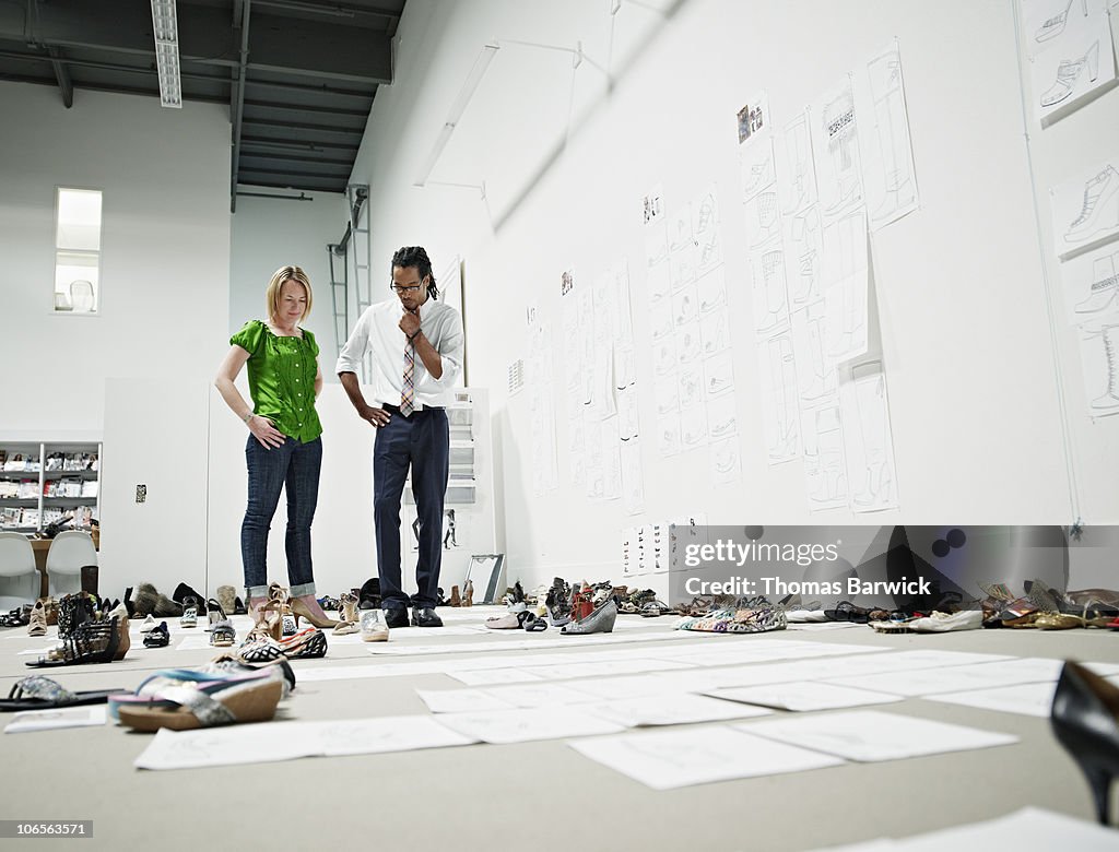Designers examining sample shoes on floor