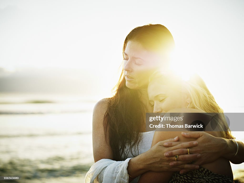 Mother and daughter embracing at sunset