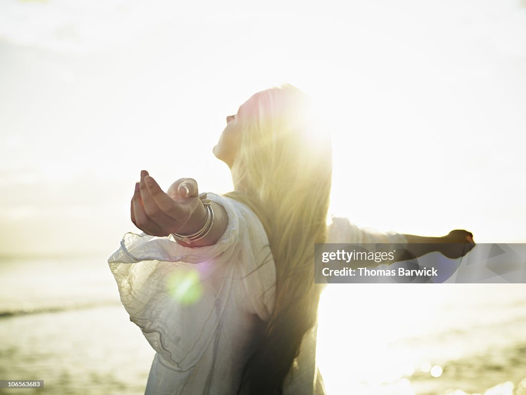 Teenage girl with arms outstretched at sunset