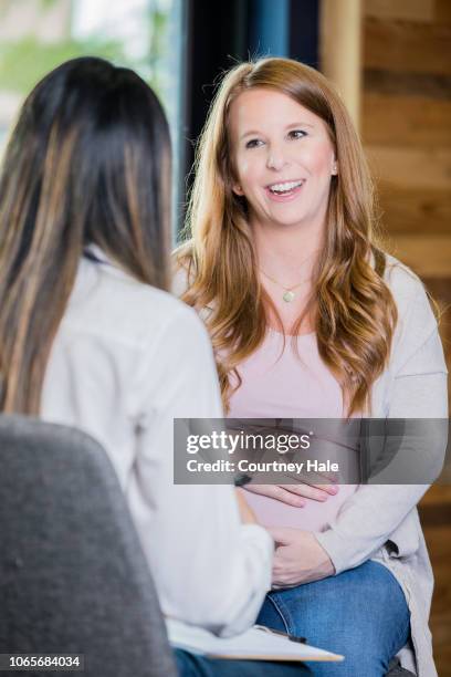 happy mother to be discussing her pregnancy with healthcare worker during childbirth class - midwife stock pictures, royalty-free photos & images