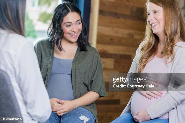 hispanic and caucasian pregnant women discussing pregnancy during prenatal support group meeting - prenatal class stock pictures, royalty-free photos & images