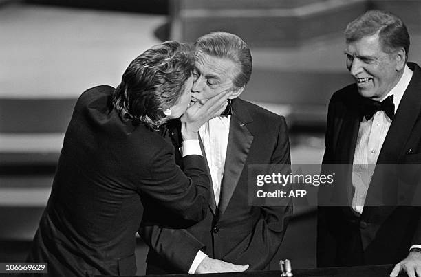 Actor Michael Douglas kisses his father US actor Kirk Douglas next to actor Burt Lancaster during the 57th Annual Academy Awards, on March 25 in...