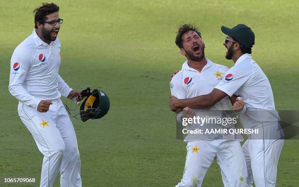 Pakistani cricketer Yasir Shah celebrates with teammates Hasan Ali and Imam-ul-Haq after taking the final wicket of New Zealand batsman Trent Boult...