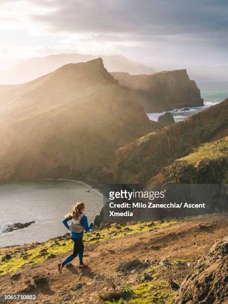 female trail runner traverses trail above coastline, cliffs - cliff stock pictures, royalty-free photos & images