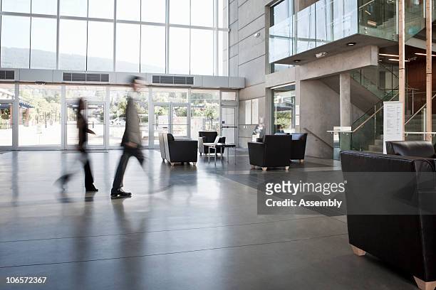 business colleagues blurred walking through office - lobby foto e immagini stock