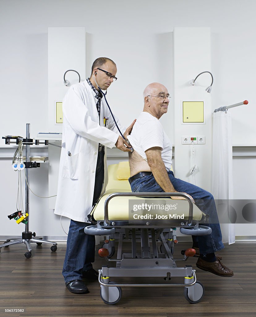 Doctor examing senior man with stethoscope