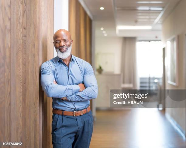 confident businessman leaning on wall with arms crossed - men beard stock pictures, royalty-free photos & images