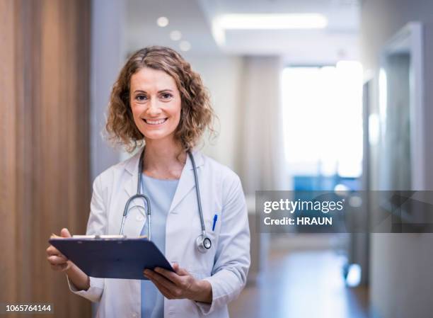 vertrouwen lachende vrouwelijke arts met klembord - woman doctor stockfoto's en -beelden