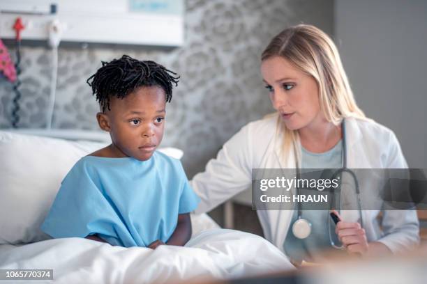 pediatrician consoling sick boy at hospital ward - childrens hospital stock pictures, royalty-free photos & images