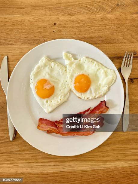 bacon and fried eggs that look like a smiley face, england - bacon and eggs stock-fotos und bilder