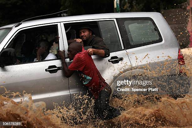 Man gets assistance through a street flooded due to Hurricane Tomas November 5, 2010 in Leogane, Haiti. The storm, which caused some flooding and...