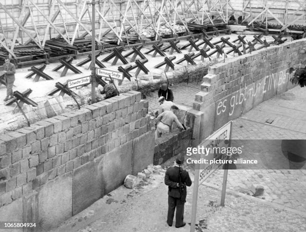 Bricklayers from East Berlin, guarded by GDR border soldiers, build up parts of Berlin Wall in Bernauer Street on the 26th of May in 1962, which...