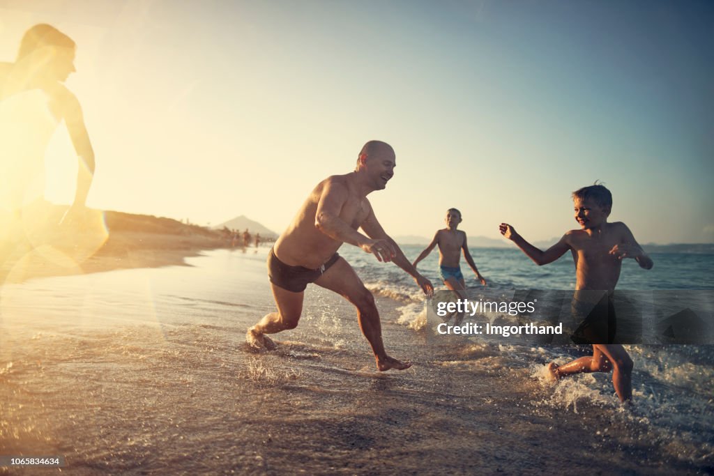 Father and kids playing tag on the beach