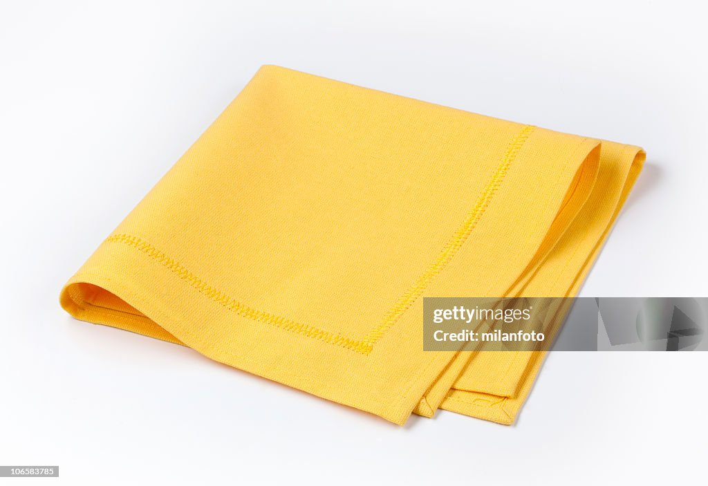 Isolated yellow napkin twice folded on white background