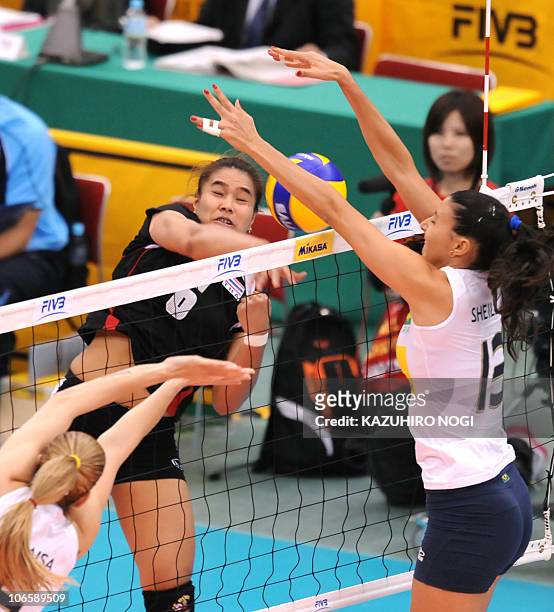 Thailand's Onuma Sittirak attacks against Brazil's Sheilla Castro and Thaisa Menezes during their second round match of the world women's volleyball...
