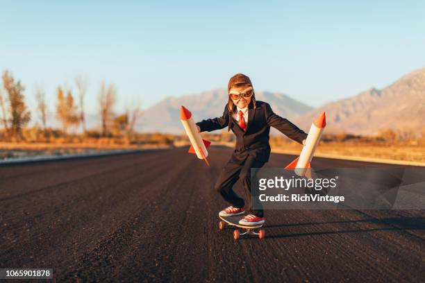 business boy holding rockets in piedi sullo skateboard - festa per il lancio pubblicitario foto e immagini stock