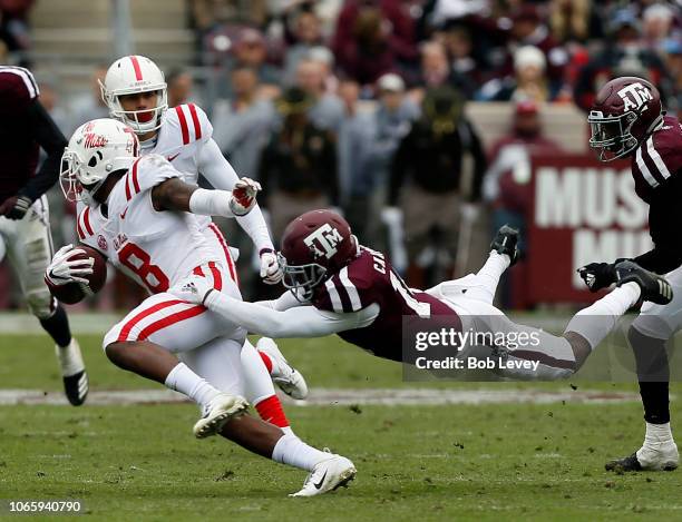 Elijah Moore of the Mississippi Rebels is tackled from behind by Keldrick Carper of the Texas A&M Aggies in the fourth quarter at Kyle Field on...