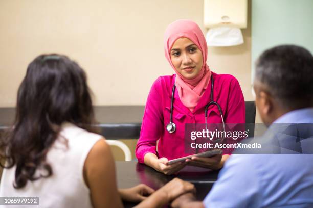 female muslim doctor consulting with patients - indonesian ethnicity stock pictures, royalty-free photos & images