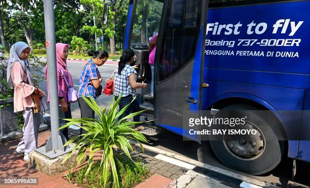 This picture taken on November 27, 2018 shows family members of the victims of Lion Air flight JT 610 boarding a bus provided by Lion Air after their...