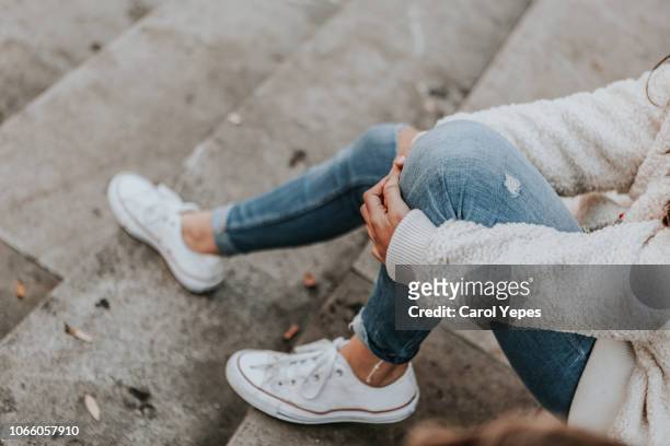 female feet in jeans and sports shoes - zapato de tela fotografías e imágenes de stock